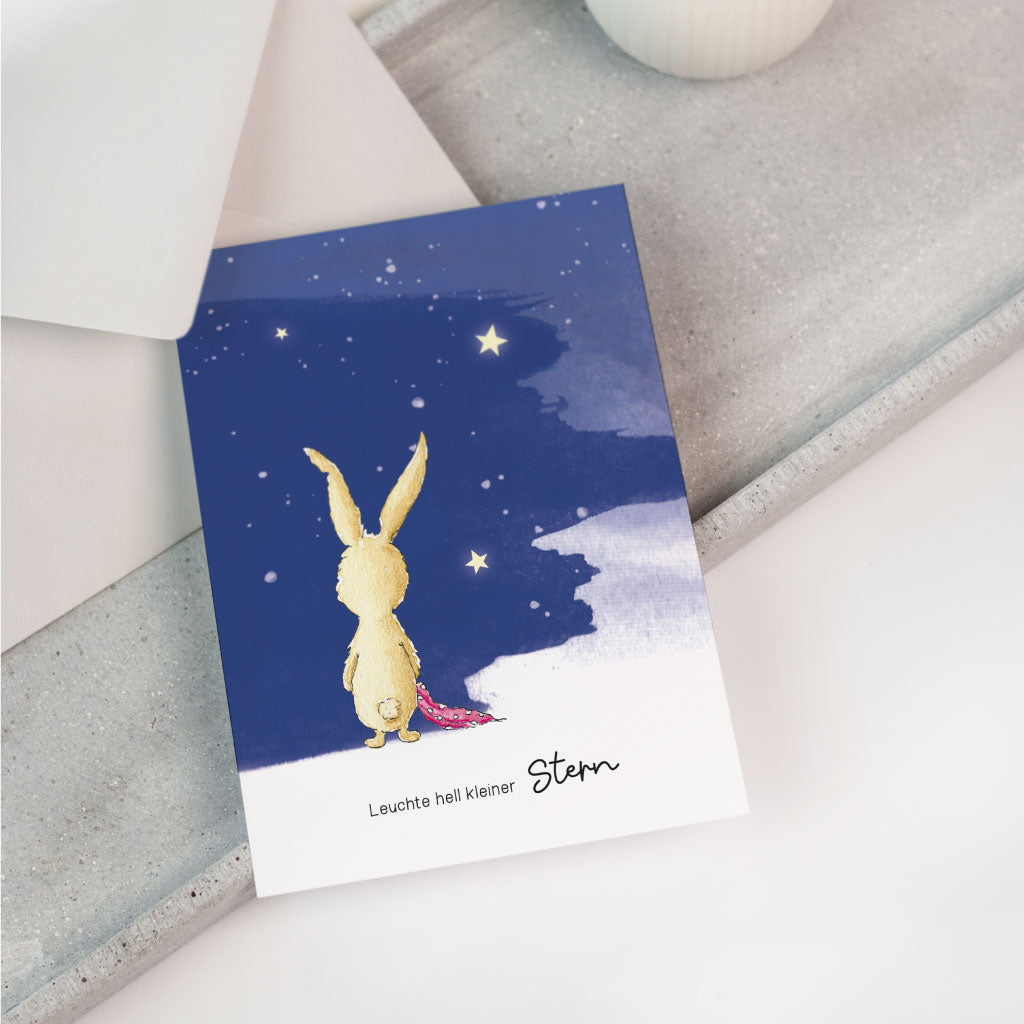 Handgemaltes Hasen Aquarell Motiv, Hase steht mit Rücken zu Betrachter und hält Schnuffeltuch in den Pfoten