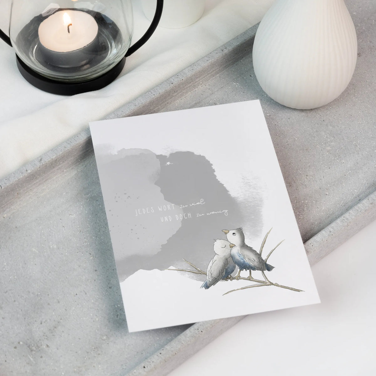 Trauerkarte mit zwei Aquarellvögeln und Trauerspruch, liegend auf Tablett neben Teelicht, als Trostgeschenk bei Trauer und Sternenkind