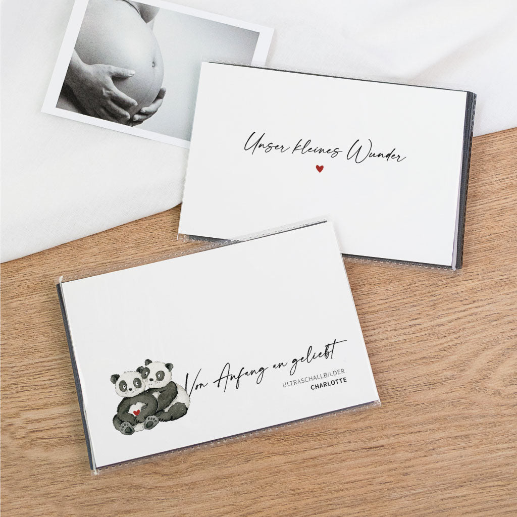 Ultraschallbilder Album als Aufbewahrung: zwei Einsteckalben auf Holztisch, oben „Unser kleines Wunder“, unten Panda-Motiv „Von Anfang an geliebt“ – Schwangerschaft Geschenk für Fotos und Schutz für Bilder.