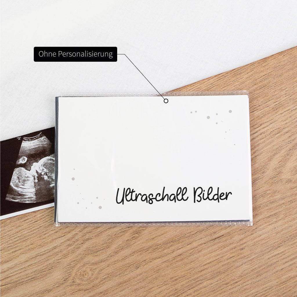 Ultraschallbilder Aufbewahrung ohne Personalisierung: schwarz-weiß Einsteckalbum „Ultraschall Bilder“ mit Hinweis „Ohne Personalisierung“, Ultraschallfoto liegt daneben.
