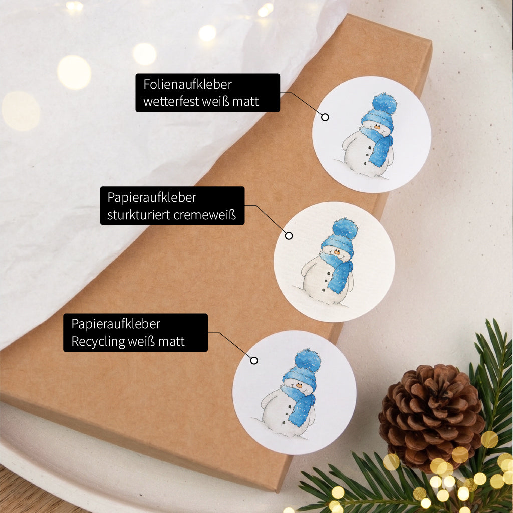 Drei runde Sticker mit blauem Schneemann Motiv zeigen die Auswahl verschiedener hochwertiger Aufkleber Materialien.
