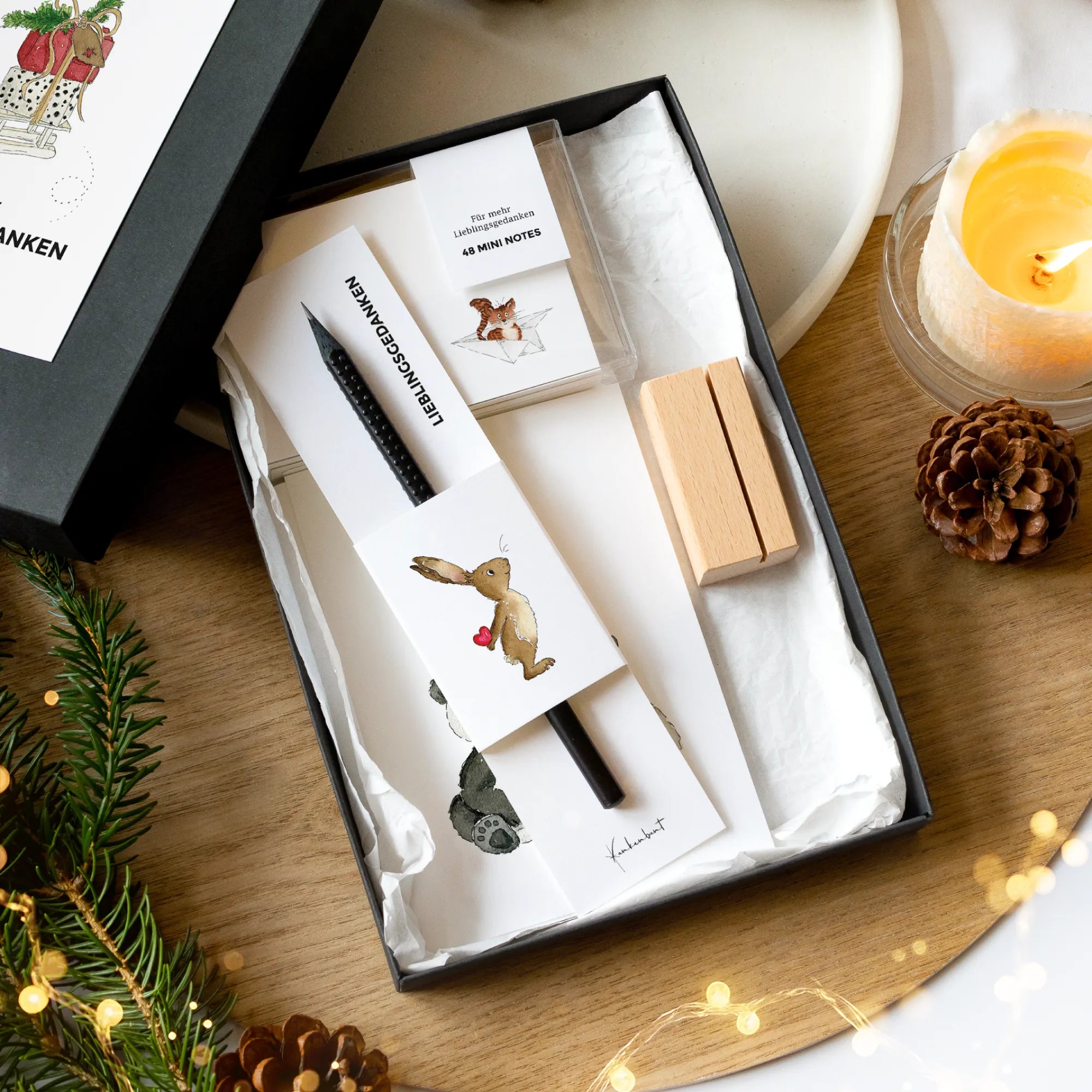 Geöffnete schwarze Geschenkbox Weihnachten mit 12 Karten mit Aquarell Motiv, 48 Mini Notes, Holz-Kartenhalter und schwarzem Design Bleistift