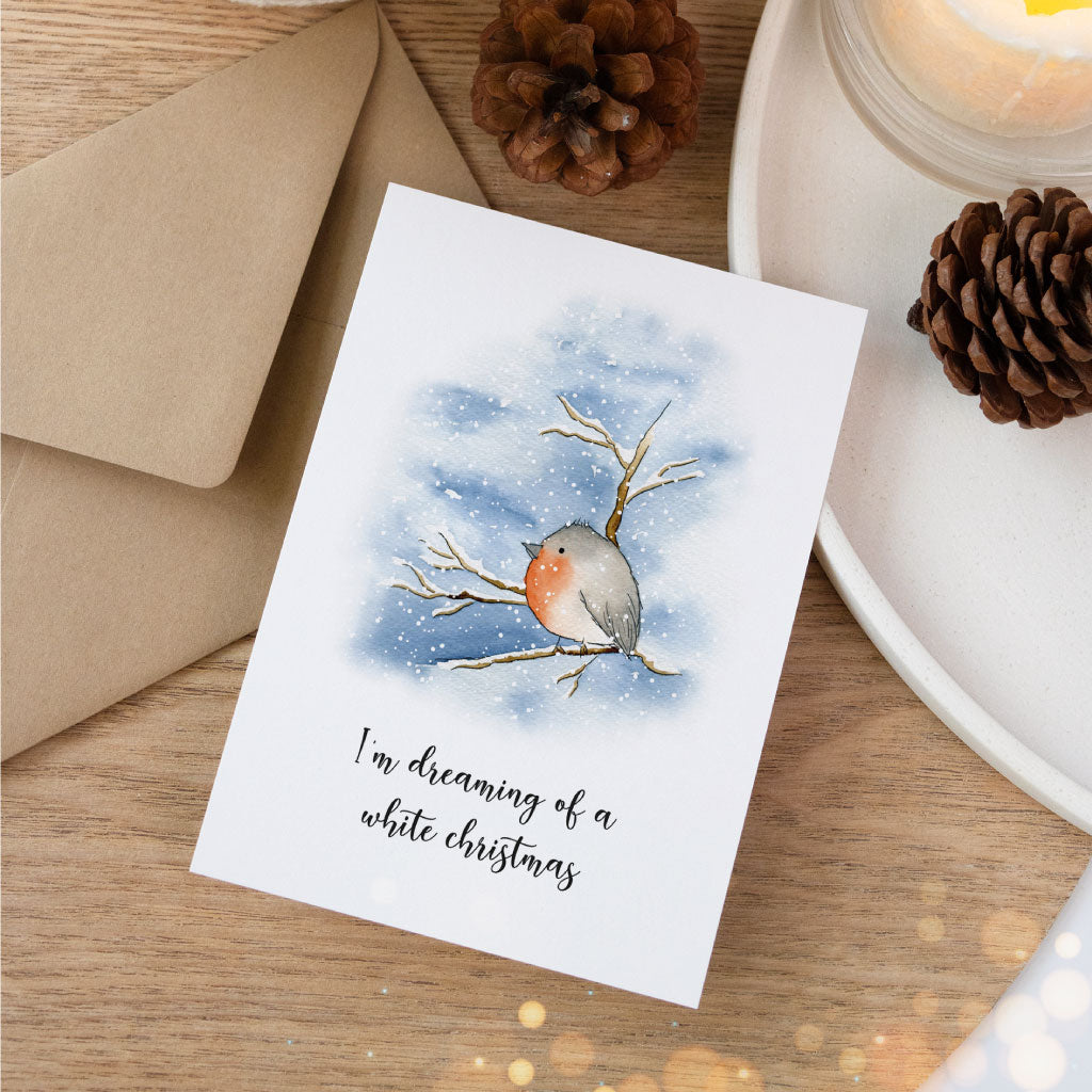 Winterliche Grußkarte mit Rotkehlchen auf einem Ast, kombiniert mit Kraftpapierumschlag und Naturdeko – perfekte Ergänzung beim Weihnachtsgeschenke verpacken.