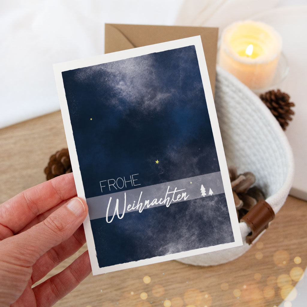 Stimmungsvolle Weihnachtskarte mit „Frohe Weihnachten“-Schriftzug, in einer Hand gehalten – ideal für persönliche Grüße oder als liebevolle Geschenkbeigabe.