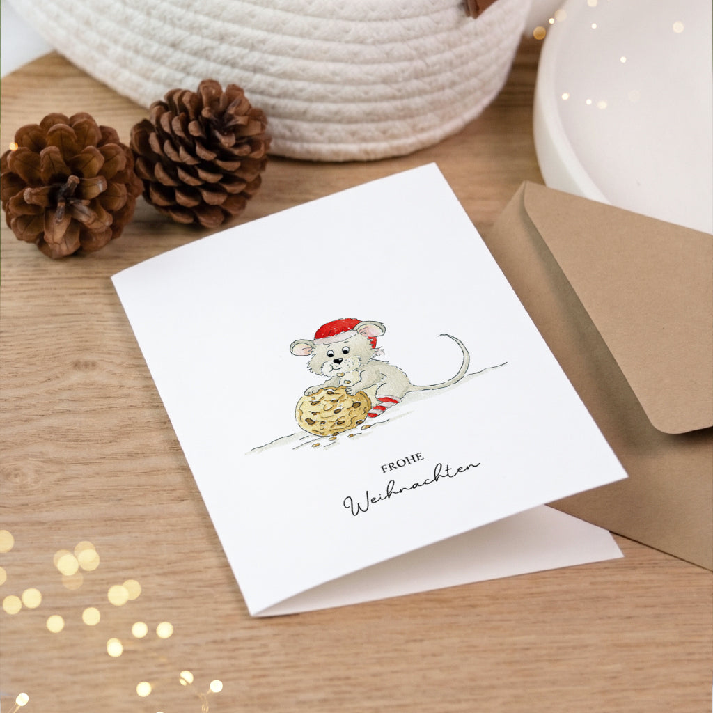 Hochwertige Weihnachtskarte als Klappkarte mit handgemaltem Maus Aquarell Motiv auf Holztisch mit Tannenzapfen.