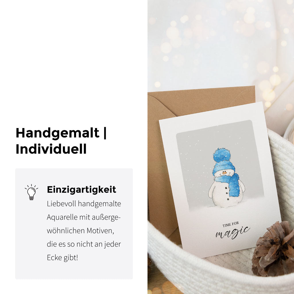 Detailansicht der Aquarell-Weihnachtskarte mit Schneemannmotiv und Text „Time for magic“, präsentiert im Korb mit Kieferzapfen und Kerze, handgemalte Winterkarte im künstlerischen Stil.