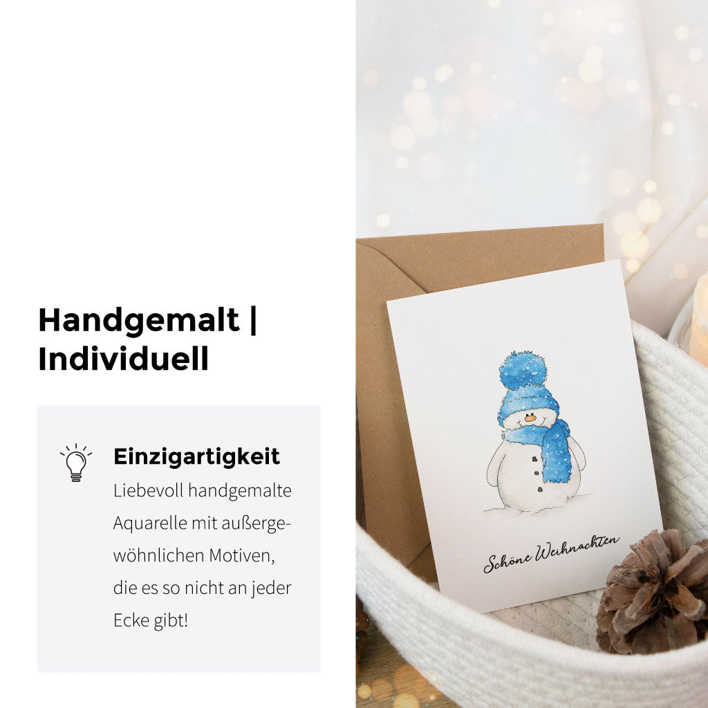 Handgemalte Aquarell-Weihnachtskarte mit Schneemann und braunem Umschlag, präsentiert mit festlicher Winterdeko – liebevoll und individuell gestaltet.