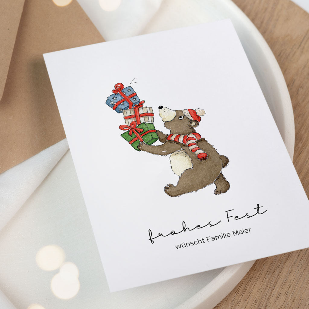 Bär mit rot weißer Mütze und Schal balanciert drei Geschenke