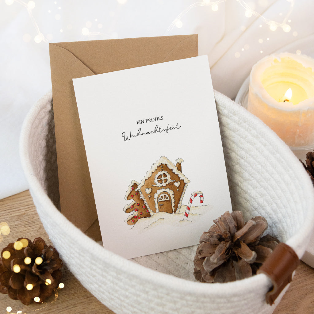 Postkarte mit einem Lebkuchenhaus im Schnee. Ein winterliches Aquarell Motiv für den gemütlichen Advent.