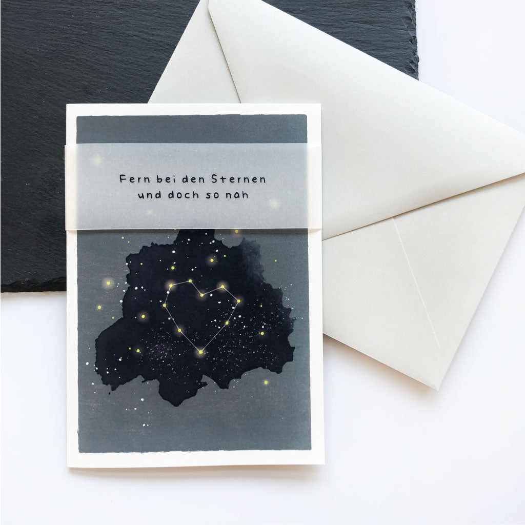 Trauerkarte mit Trauerspruch "Fern bei den Sternen und doch so nah" liegt auf Kuvert