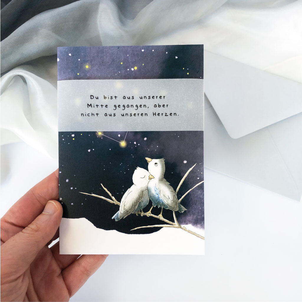 Trauerkarte in Hand vor Hintergrund aus hellgrauem Kuvert