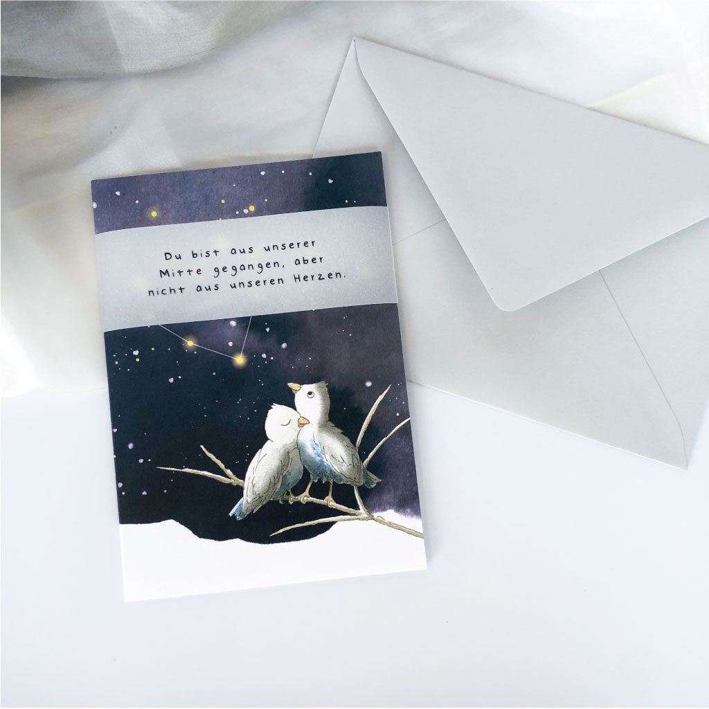 Klappkarte mit Aquarell Vögeln auf Ast und Sternenhimmel liegt neben hellgrauem Kuvert