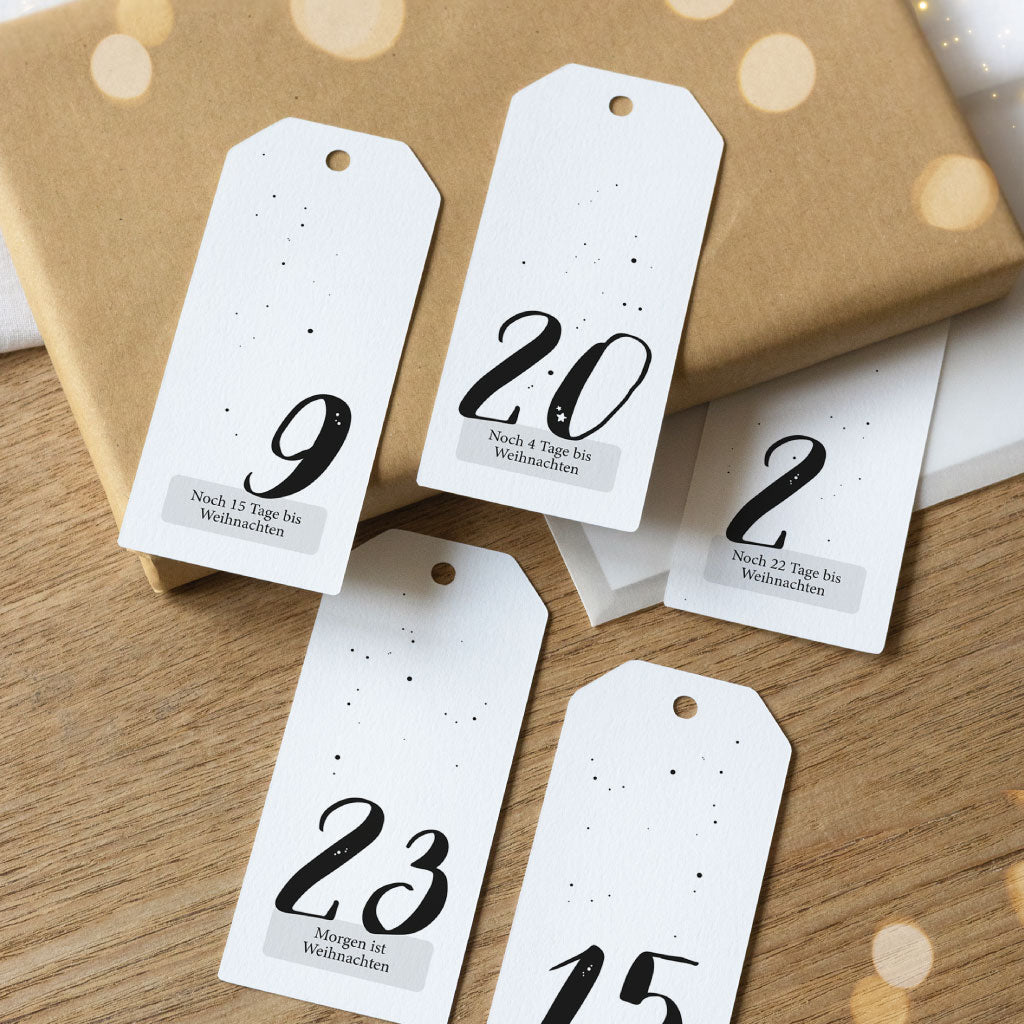 Adventskalender Anhänger liegen auf kleinen Geschenken und Kuverts