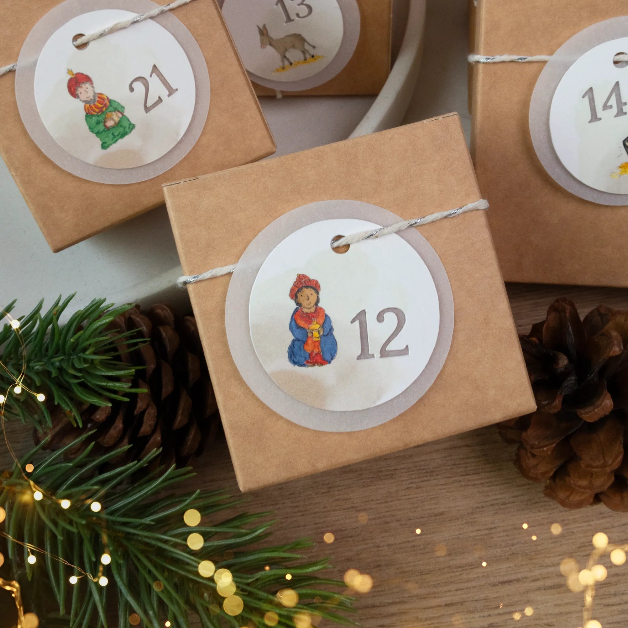 Nahaufnahme eines runden Adventskalender Anhängers mit der Zahl 12 und einem König Aquarell Motiv auf einer Schachtel.