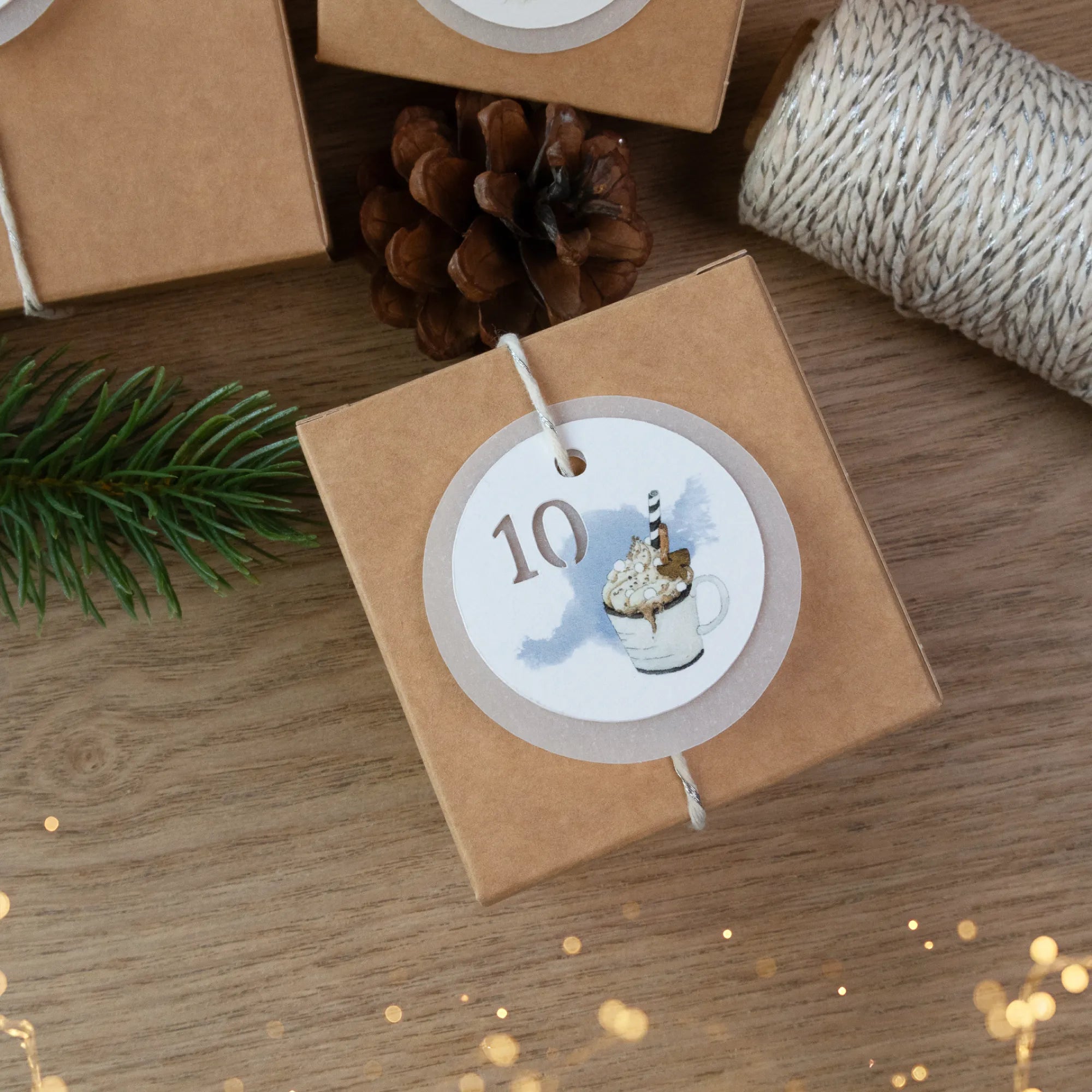 Adventskalender Schachtel dekoriert mit Kordel und detailreichem handgemaltem Kakao Aquarell Motiv auf dem Geschenkanhänger.