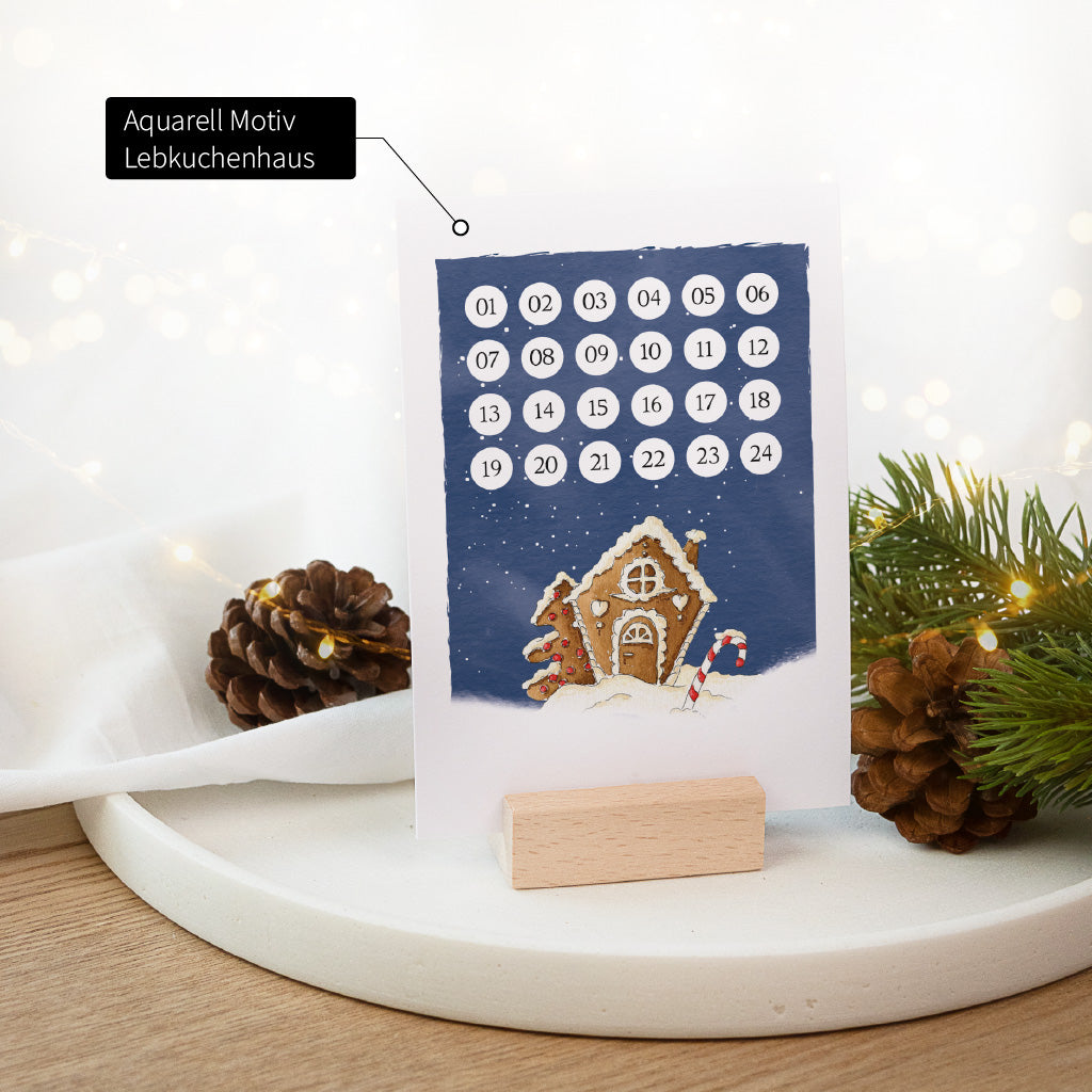 Adventskalender Karte zum Abhaken mit einem verschneiten Lebkuchenhaus Aquarell Motiv im Buchenholzhalter.