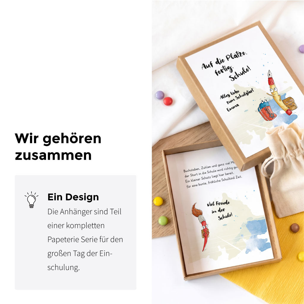 Geöffnete Geschenkschachtel mit passender Karte und Anhänger der Serie mit dem Stifte Aquarell Motiv zur Einschulung.