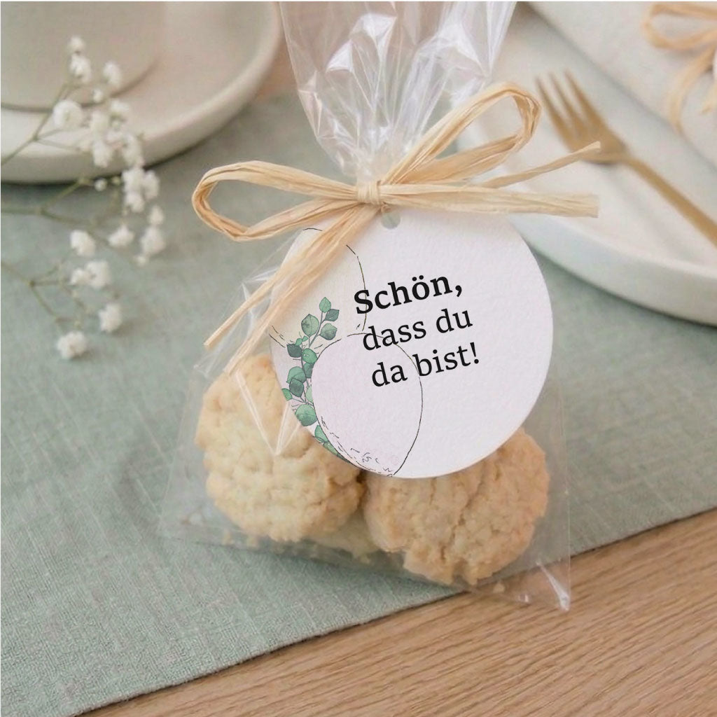 Süßes Gastgeschenk mit Keksen und rundem Anhänger mit der Aufschrift Schön dass du da bist für die festliche Tischdeko.