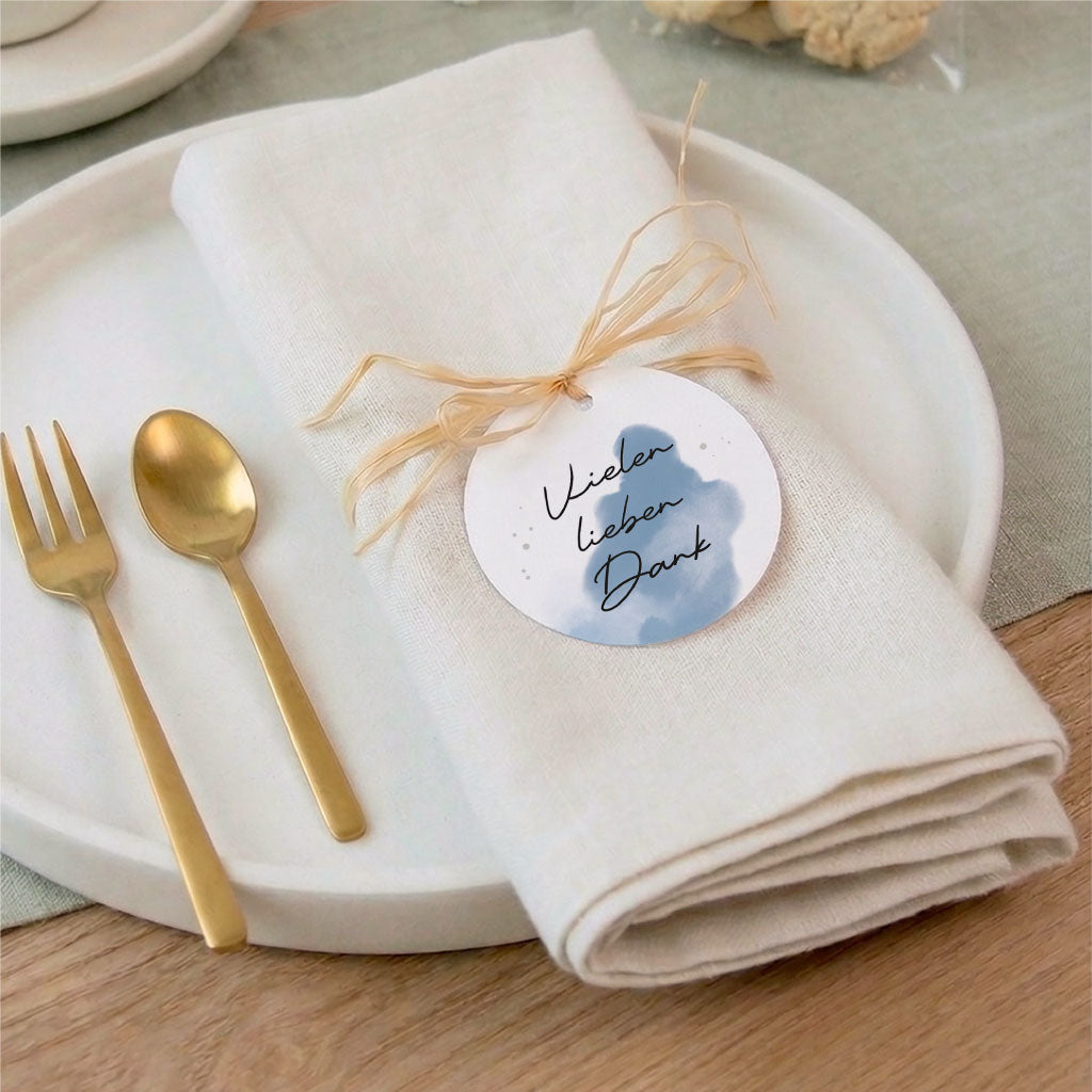 Festliche Tischdeko zur Kommunion mit goldenem Besteck und einem Anhänger als Dankeschön auf einer Serviette.