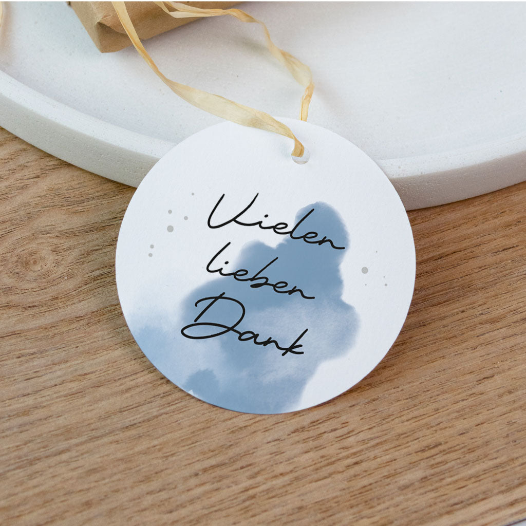 Kleines Gastgeschenk in Kraftpapier verpackt mit einem runden Anhänger und blauem Aquarell Motiv für die Taufe.