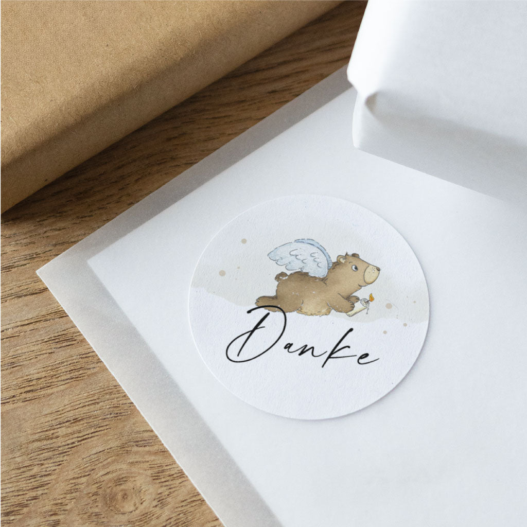 Detailaufnahme eines runden Aufklebers mit handgemaltem Engel-Bär und Dankeschön Schriftzug für Feier, Gastgeschenk oder Papeterie