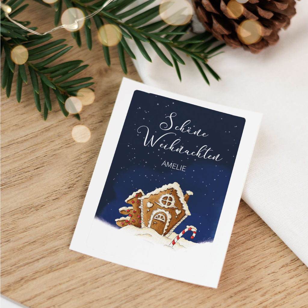 Personalisierbarer Aufkleber für Grabkerzen zu Weihnachten mit handgemaltem Aquarell-Lebkuchenhaus und dem Schriftzug „Schöne Weihnachten“.