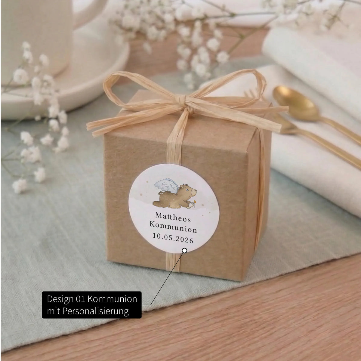 Kraftpapier-Geschenkbox mit personalisiertem Kommunion-Aufkleber Design 01, Aquarell Motiv Engelbär mit Name und Datum, Raffiaschleife