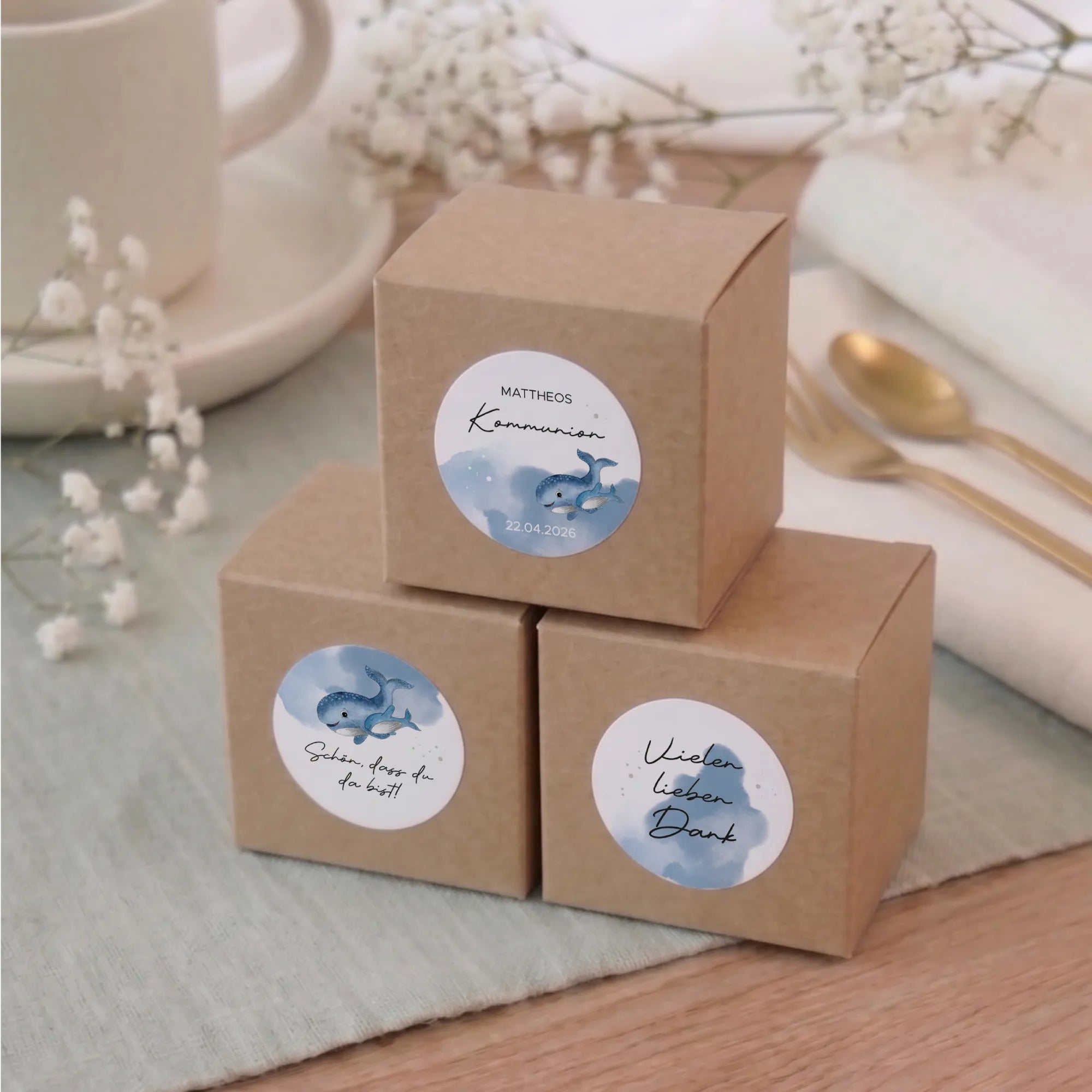 Drei runde Aufkleber zur Kommunion und Konfirmation mit blauem Aquarell Motiv Wal auf Kraftpapier-Geschenkboxen, Designs mit Name, Schön dass du da bist und Vielen lieben Dank