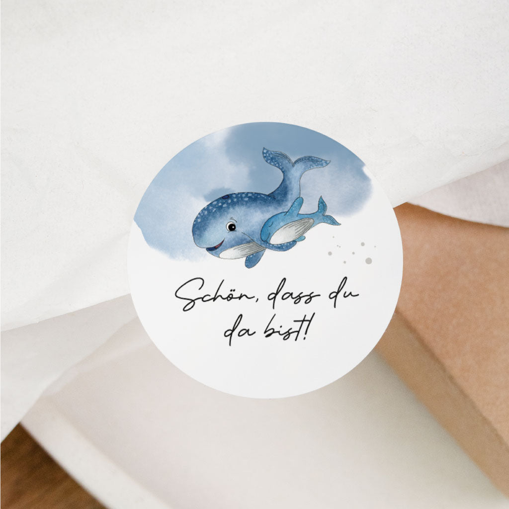 Sticker „Schön, dass du da bist“ auf Geschenkverpackung – runder Aufkleber mit zwei Walen für Gastgeschenke bei Hochzeit, Geburtstag oder Taufe