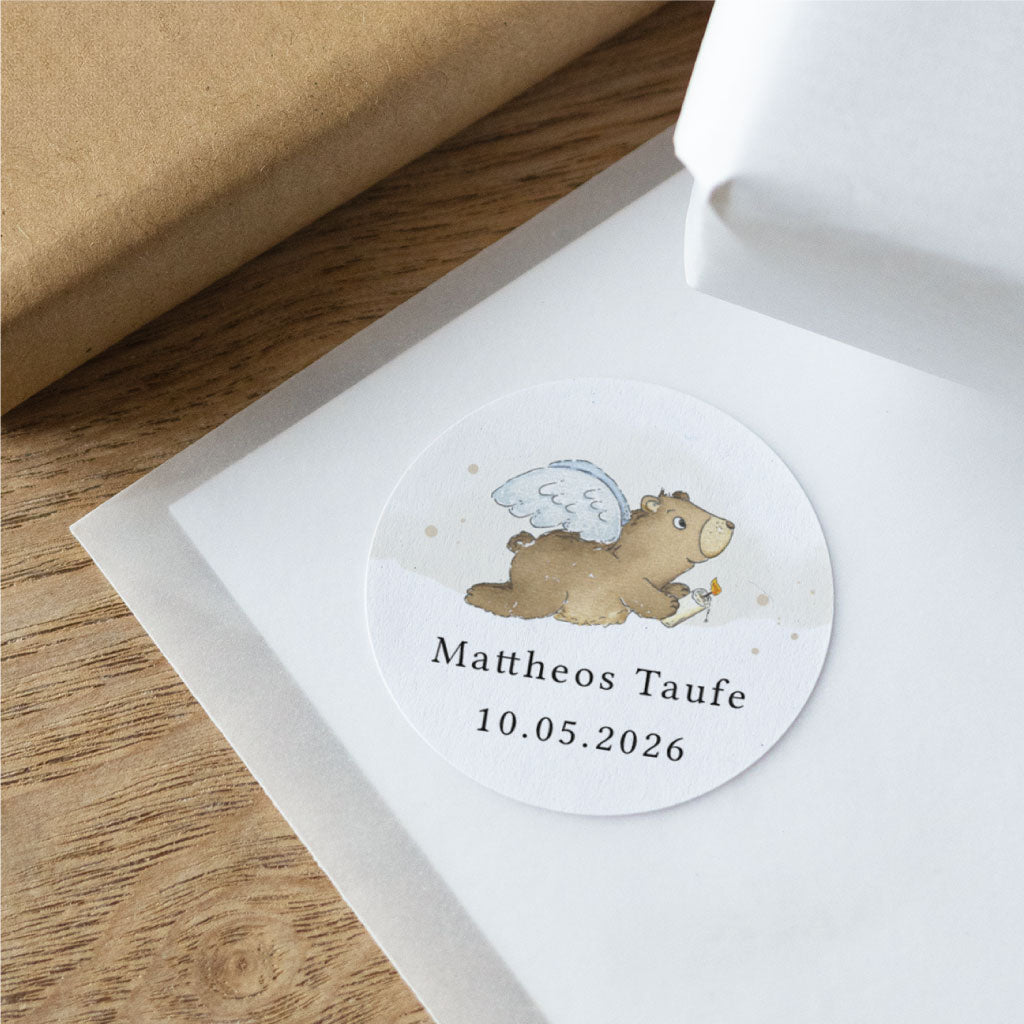 Detailaufnahme eines personalisierten Taufe Aufklebers mit Engel-Bär auf strukturierter Oberfläche, individuell mit Name und Datum