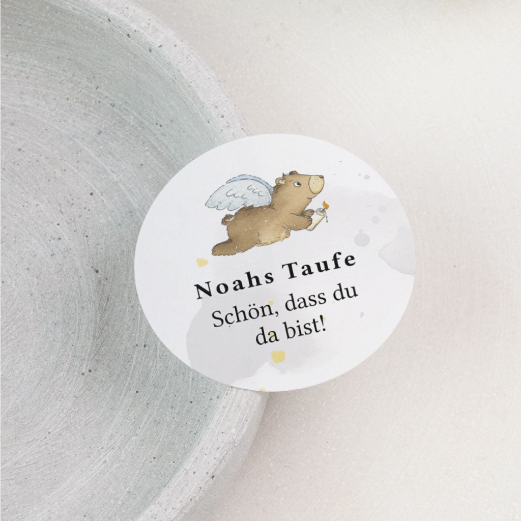 Runder personalisierter Aufkleber zur Taufe mit handgemaltem Bärenmotiv mit Flügeln und dem Text Noahs Taufe Schön, dass du da bist.