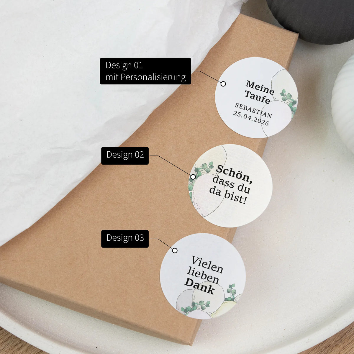 Drei runde Taufe Aufkleber auf Kraftpapier-Box mit Beschriftung der drei Designs: personalisiert, Schön dass du da bist, Vielen lieben Dank