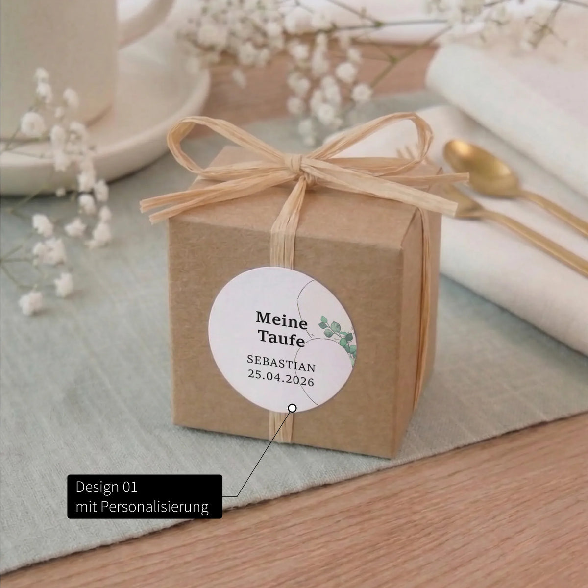 Kraftpapier-Geschenkbox mit Bast-Schleife und rundem Taufe Aufkleber Design 01, personalisiert mit Name und Datum, Aquarell Motiv