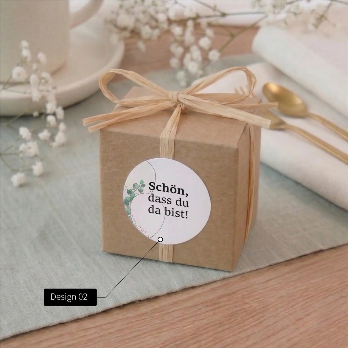 Kraftpapier-Geschenkbox mit Bast-Schleife und rundem Aufkleber Schön dass du da bist, Aquarell Motiv Eukalyptus zur Baby Taufe