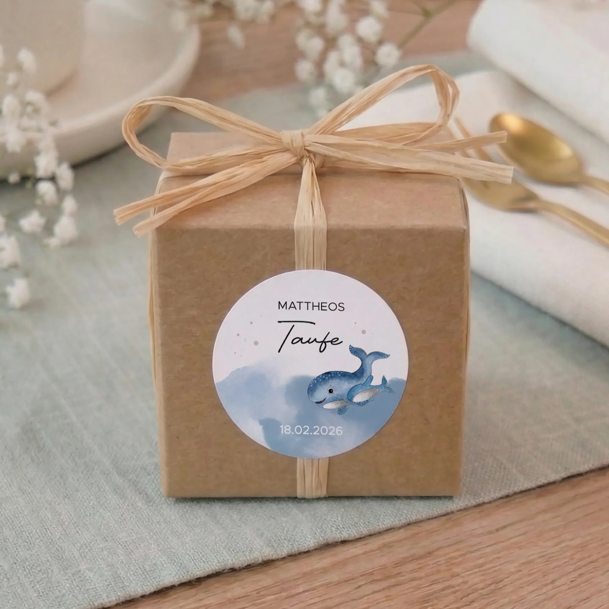 Personalisierter Taufe Aufkleber Design 01 mit Aquarell Motiv blauem Wal, Name Mattheos und Datum auf Kraftpapier-Geschenkbox mit Bast-Schleife