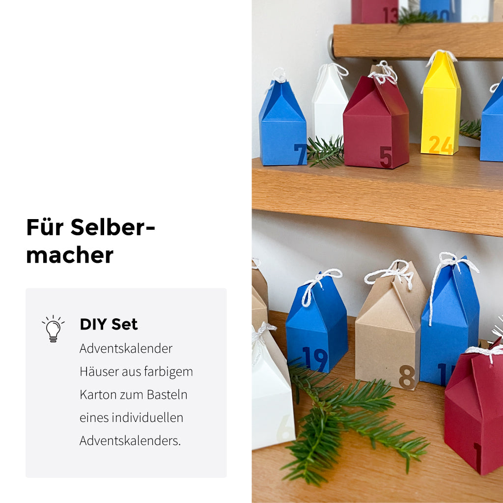 Individuell gestalteter Adventskalender zum Basteln: bunte Häuschen aus Karton mit Zahlen, dekorativ auf einem Regal arrangiert – DIY Set für kreative Weihnachten.