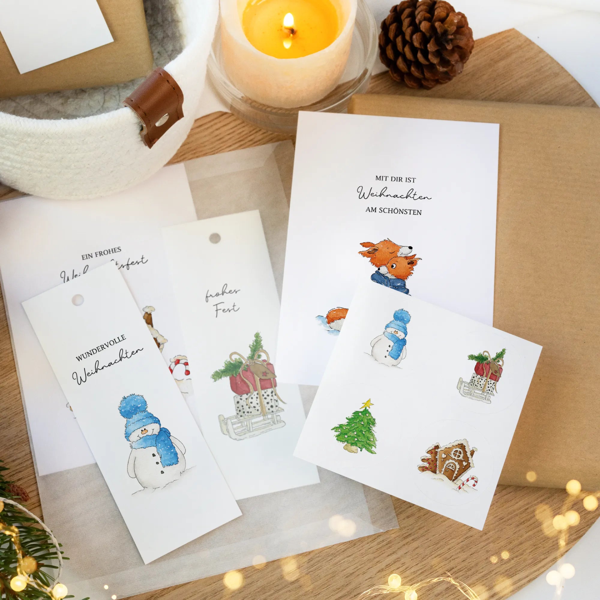 Weihnachtliches Dekoset mit Postkarten, Geschenkanhängern und Aufklebern mit Aquarell Motiven auf einem Holztisch.