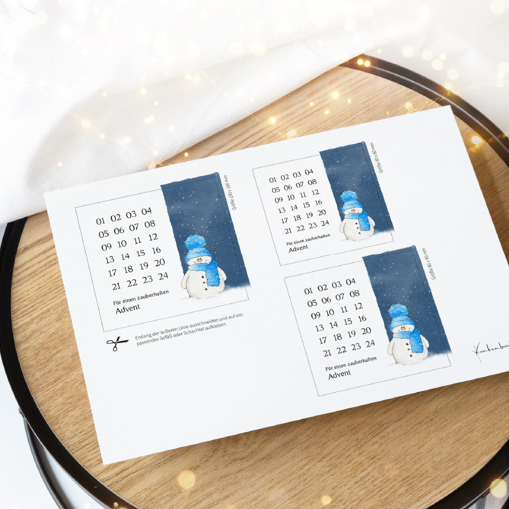 Gedruckter DIN A4 Bogen auf einem Holztablett mit drei Größen vom Schneemann Aquarell Motiv als PDF