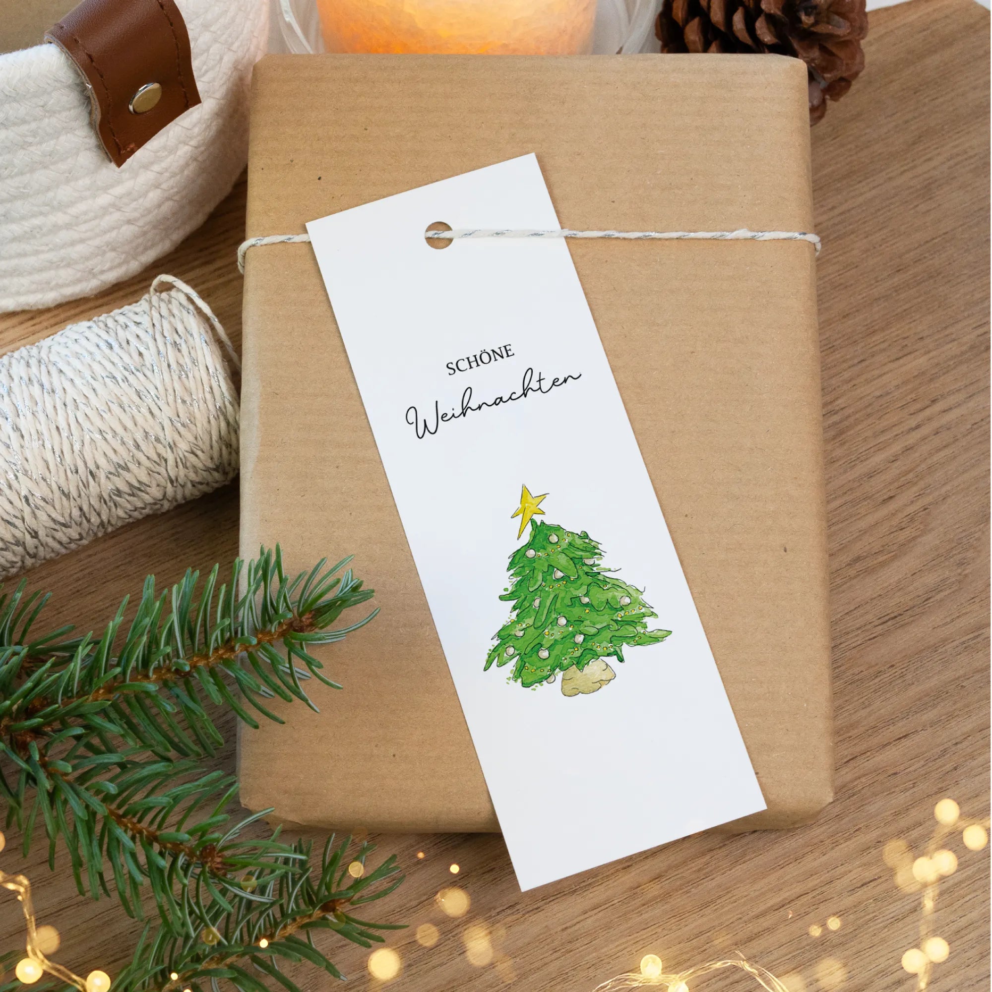 Geschenkanhänger mit handgemaltem Tannenbaum Aquarell Motiv auf braunem Paket verpackt.