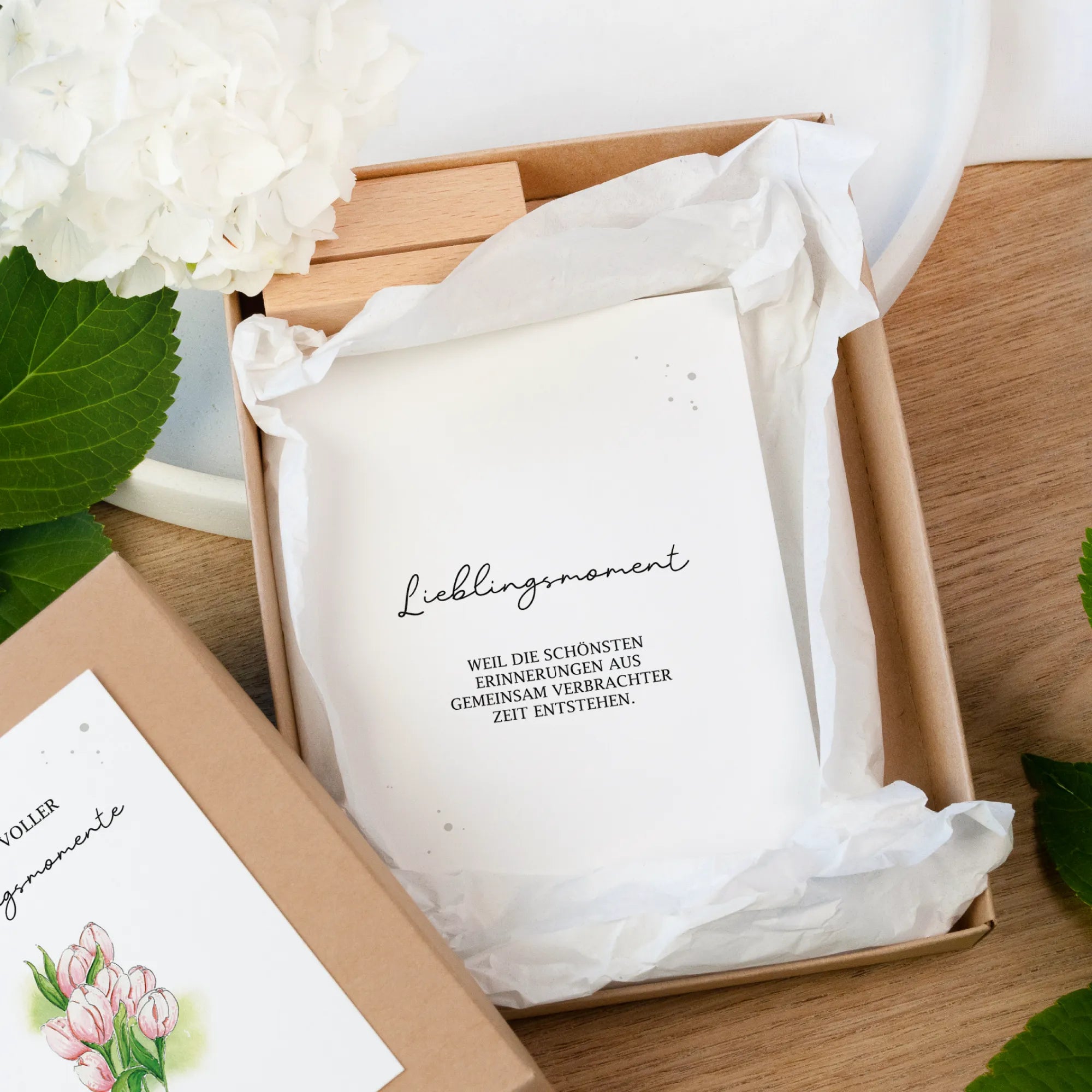 Blick in eine geöffnete Gutschein Box aus Kraftpapier. Auf der obersten Karte steht der Spruch Lieblingsmoment in schwarz.