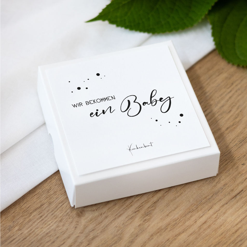 Quadratische Box mit der Titelkarte „Wir bekommen ein Baby“ – minimalistische Meilensteinkarten als Geschenk für werdende Mamas, digitaler Download als PDF.