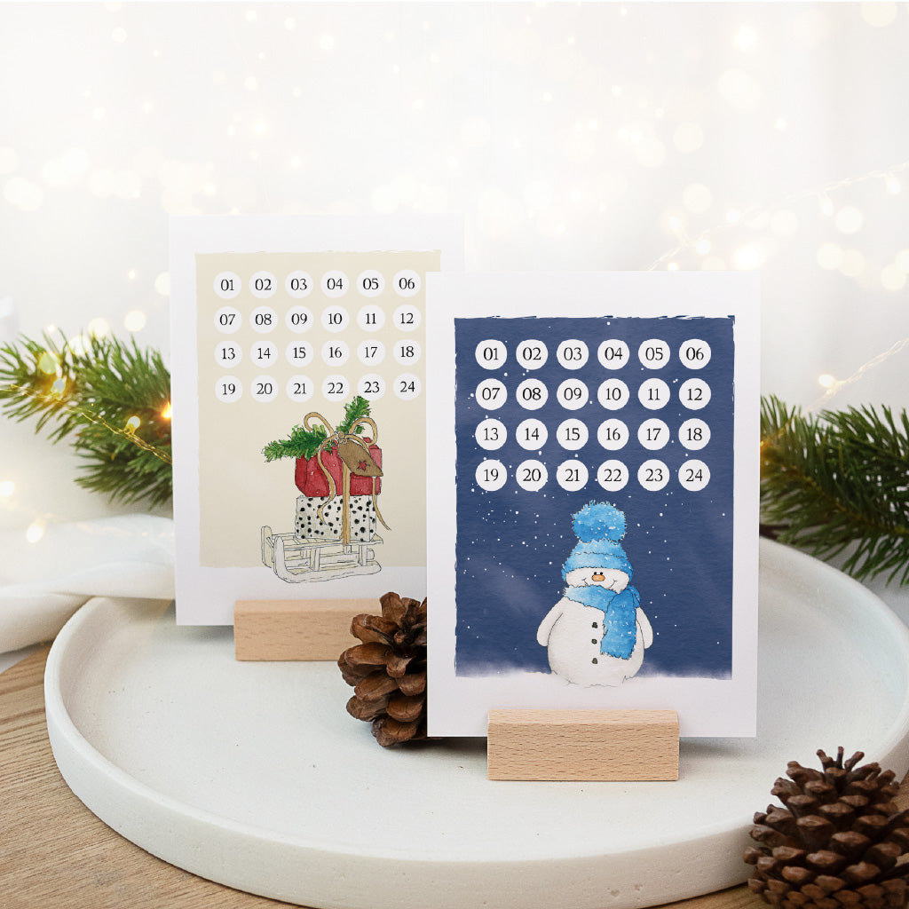 Kreativer Weihnachtskalender als Tischdeko mit Schlitten und Schneemann Aquarell Motiv auf Holzhaltern.