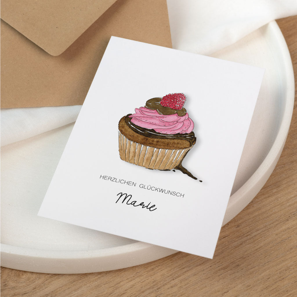 Personalisierbare Geburtstagskarte mit handgemaltem Muffin, Schriftzug „Herzlichen Glückwunsch“ und Name „Marie“ auf weißer Karte mit Umschlag.