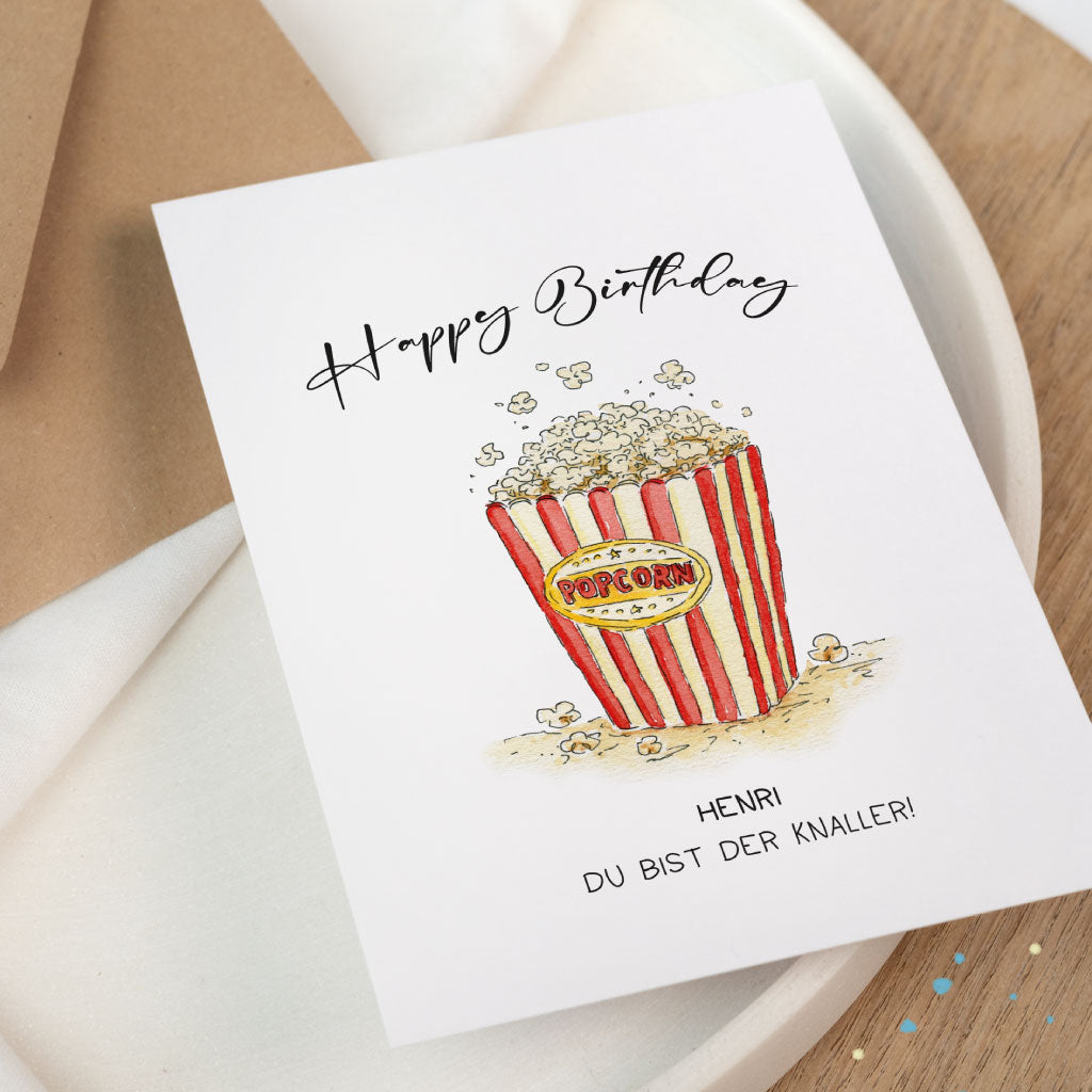 Aquarell-Geburtstagskarte mit rot-weißer Popcorntüte und Konfetti-Elementen, individualisierbar mit Namen – perfekt für Kinofans oder Zirkusliebhaber.