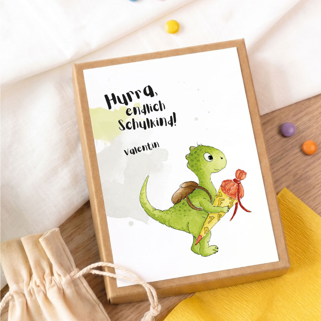Personalisierte Geschenkschachtel zur Einschulung mit grünem Dino Aquarell Motiv und Name Valentin auf braunem Karton.