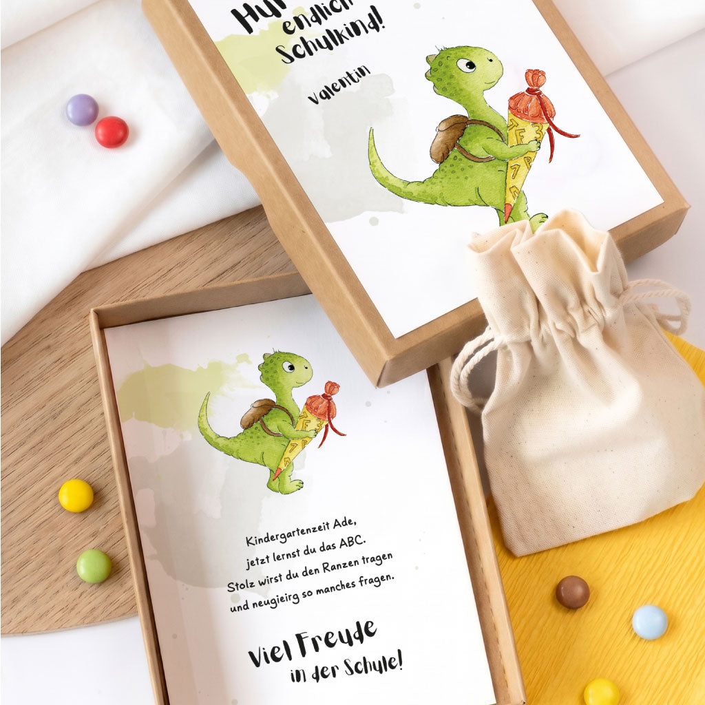 Offene Geschenkbox zum Schulbeginn mit kurzem Gedicht im Innenteil und kleinem Stoffbeutel für ein Geldgeschenk.