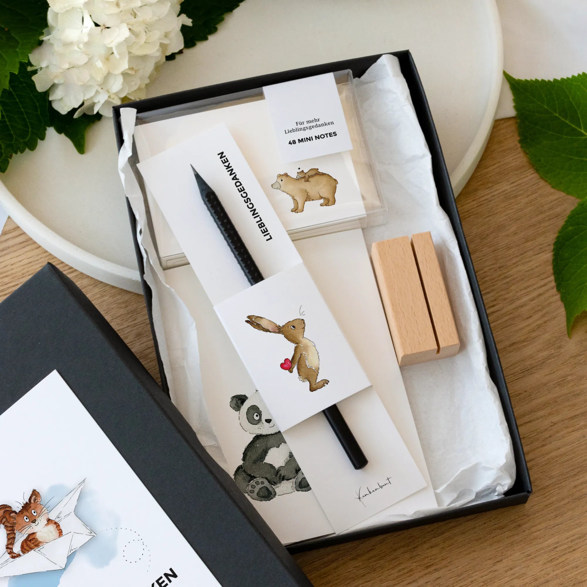 Geöffnete Geschenkbox mit 12 Karten mit Aquarell Motiven, 48 Mini Notes, Holzkartenhalter und schwarzem Design Bleistift, Geschenk für Frauen