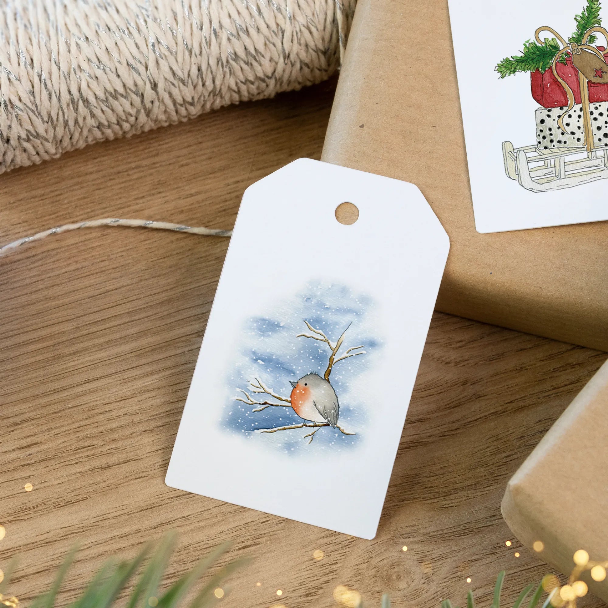 Handgemaltes Rotkehlchen Aquarell Motiv im Schnee auf einem Geschenkanhänger für die festliche Bescherung.