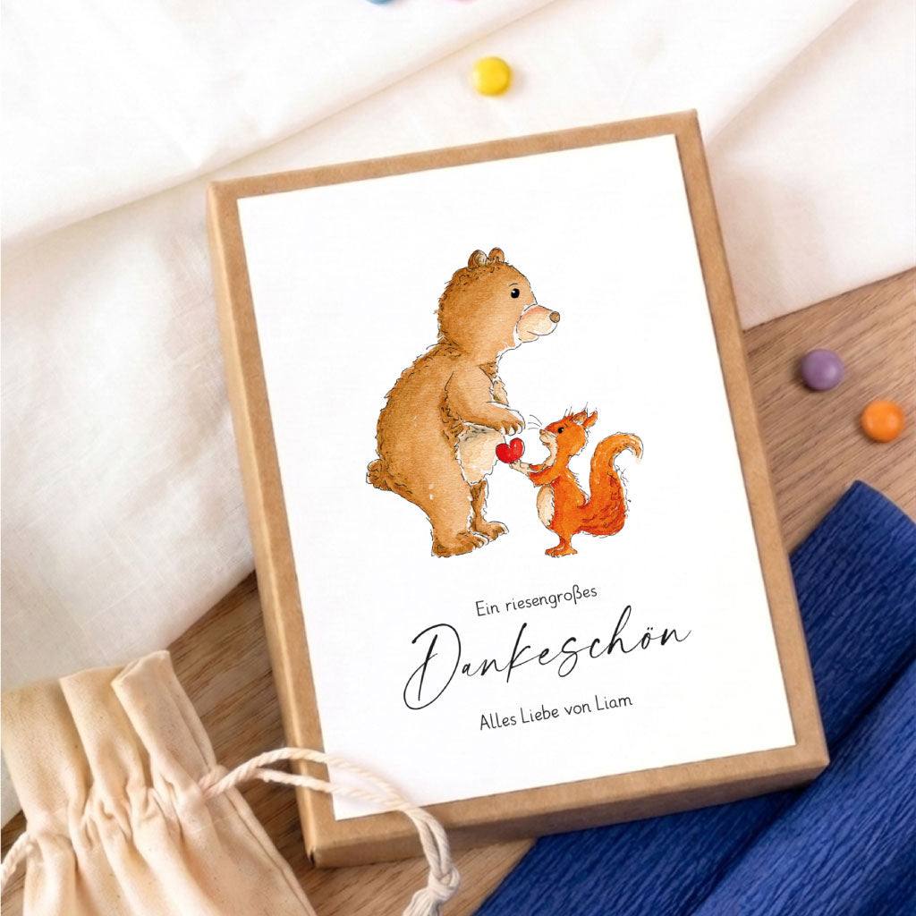 Personalisierbare Geschenkschachtel als Abschiedsgeschenk mit Bär und Eichhörnchen Aquarell Motiv auf Holztisch.