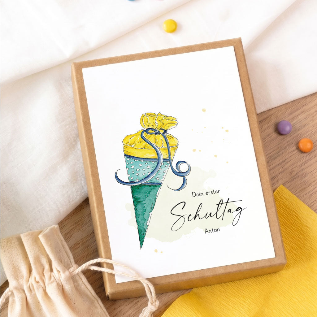Handgemaltes Schultüten Aquarell Motiv auf einer individuellen Geschenkbox zur Einschulung neben bunten Schokolinsen.